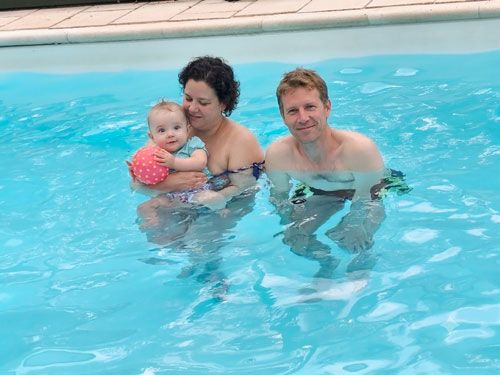 Couple avec bébé dans la piscine chauffée du gîte